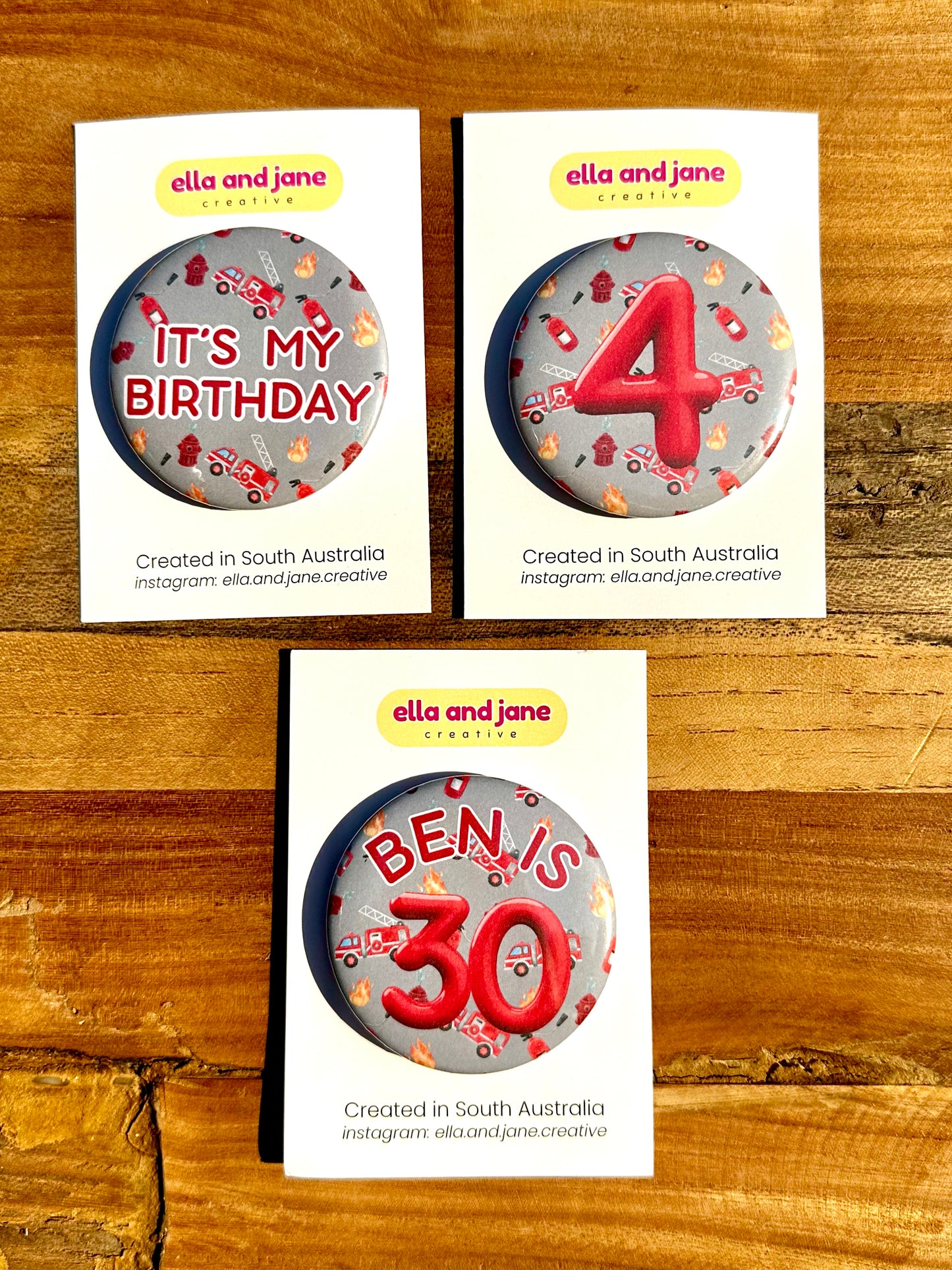 Three firetruck birthday badges. One has the text 'It's my birthday' The other has the number '4' and the third custom badge is 'Ben is 30'.
The backgrounds of the badges are a light rey colour with pictures of flames, fire extinguishers and firetrucks.